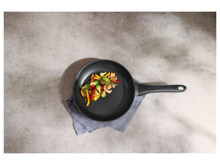 Eine schwarze Pfanne mit sautierten Gemüse.