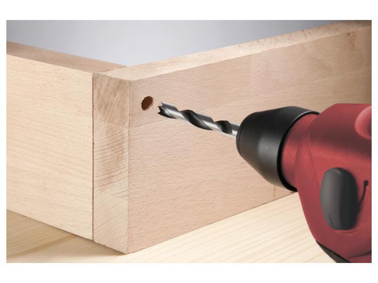 Bohrmaschine bohrt ein Loch in ein Holzteilstück einer Schublade.
