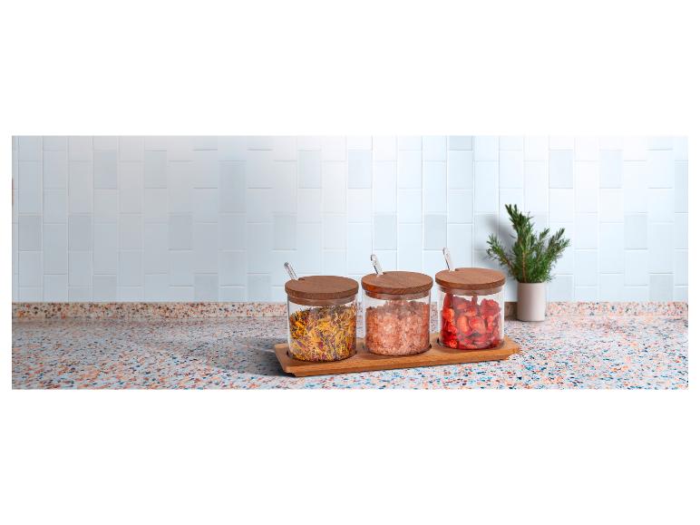 Getrocknete Kräuter, rosa Himalaya-Salz und gefriergetrocknete Erdbeeren in Glasbehältern auf einer Arbeitsplatte.