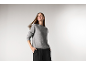 Frau in einem grauen Strickpullover und einer schwarzen Hose.