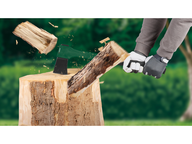 Person spaltet Holz mit einer Axt auf einem Hackklotz, Holzsplitter fliegen weg.