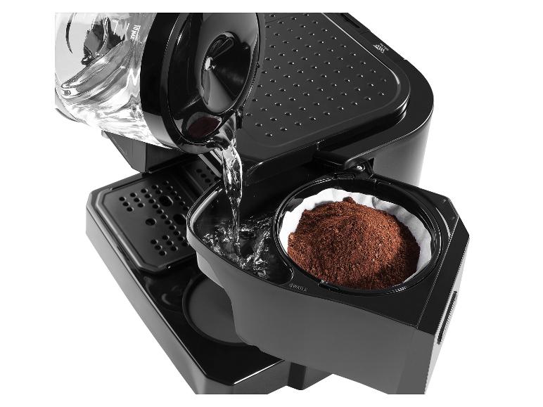 Wasser wird in eine Kaffeemaschine mit gemahlenem Kaffee im Filter gegossen.