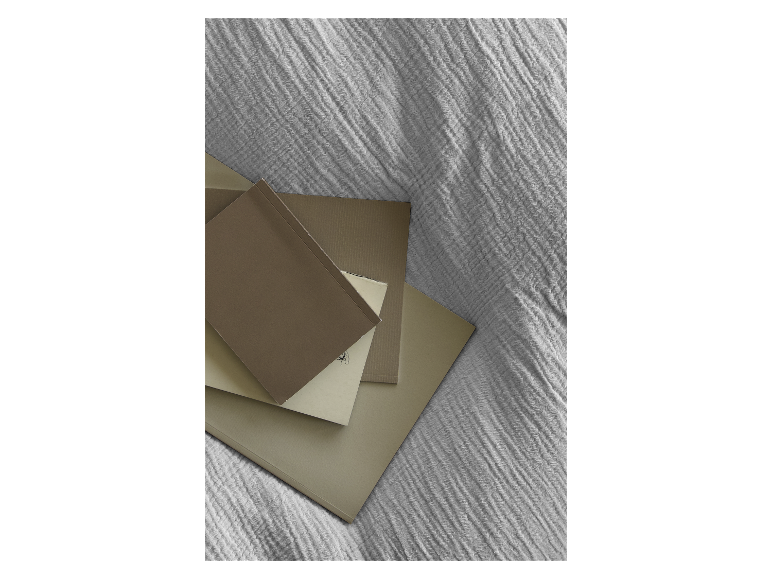 Beige und braune Notizbücher und Blöcke auf einem strukturierten Stoff gestapelt.