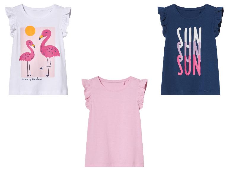 Drei Mädchen-T-Shirts mit Rüschen, eines mit Flamingos, eines mit 'SUN' und eines einfarbig rosa.