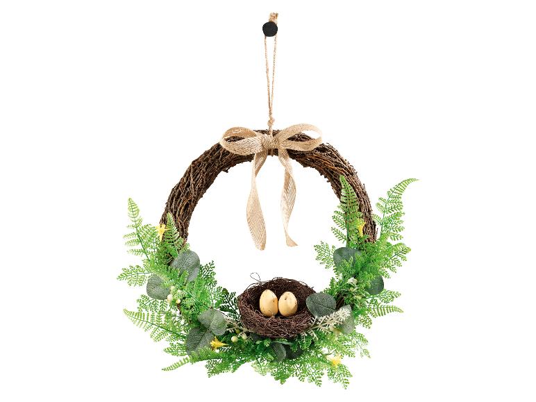 Osterkranz mit einem Nest und zwei Eiern, verziert mit grünem Laub und einer Juteschleife.