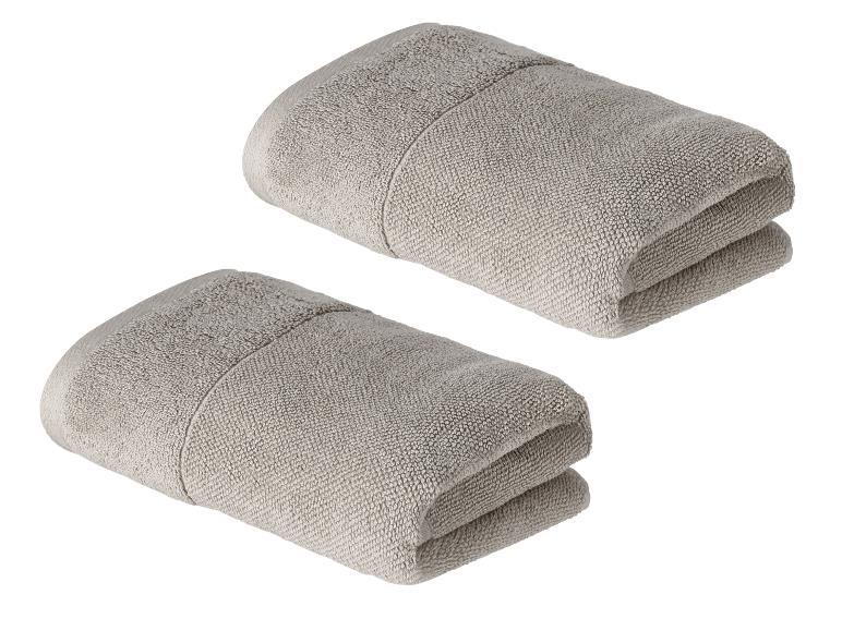 Zwei Stapel graue Handtücher auf weißem Hintergrund.