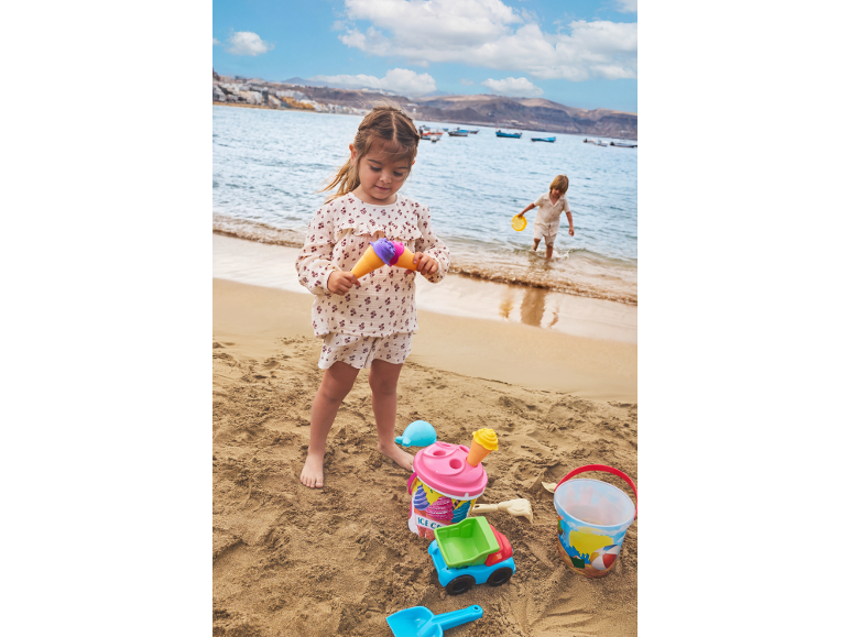 Kinder spielen am Strand mit Sandspielzeug, Eimern und Schaufeln.