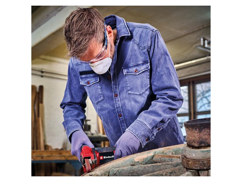 Mann mit Schutzausrüstung schleift Holz mit einem Elektrowerkzeug.