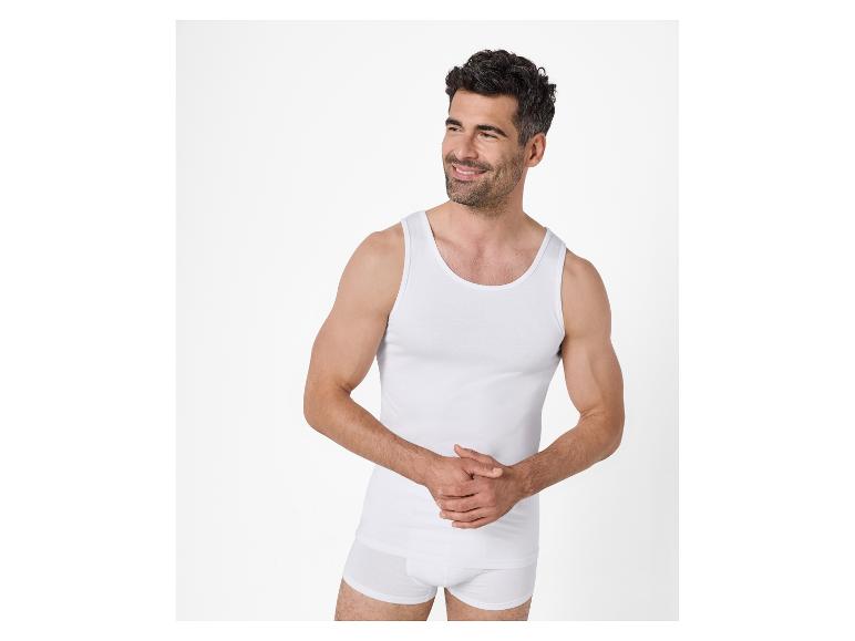 Lächelnder Mann in weißem Unterhemd und Boxershorts