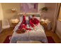 Ein Paar in passenden roten Karo-Pyjamas entspannt auf einem Bett in einem gemütlichen Schlafzimmer.