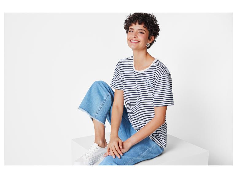 Eine Frau trägt ein gestreiftes T-Shirt, blaue Jeans und weiße Sneakers.