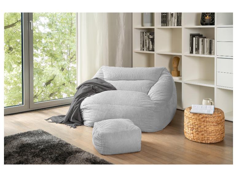 Hellgrauer Cord-Sitzsack und Hocker in einem Wohnzimmer mit Fenster und Bücherregal.