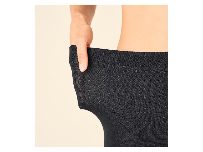 Frauenhand zieht an schwarzer Strumpfhose, um deren Elastizität zu zeigen.