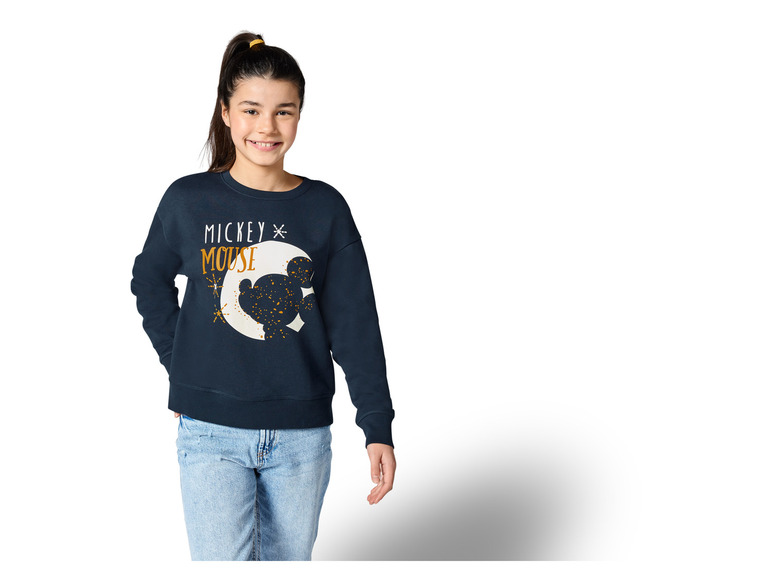 Ein Mädchen trägt einen blauen Pullover mit Mickey Mouse Motiv.