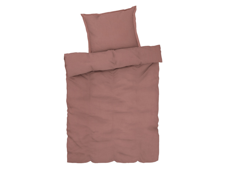 Eine rosa Bettdecke mit einem Kissen.