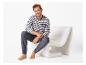 Mann in gestreiftem Shirt und dunkelgrauer Jogginghose sitzt auf einem weißen Sessel.