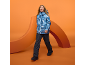 Frau in blauer Skijacke und dunkler Skihose auf orangefarbenem Hintergrund.