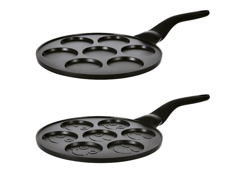 Pfannkuchenpfanne mit 7 Vertiefungen, eine leer, die andere mit Smiley-Gesichtern.