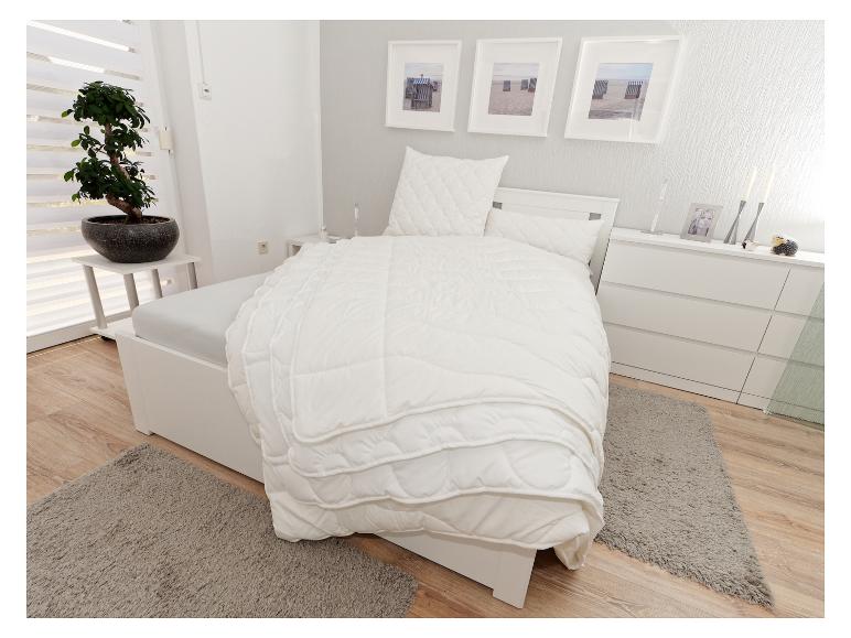 Schlafzimmer mit weißem Bett, Bettwäsche, Kommode und einem Bonsai-Baum.