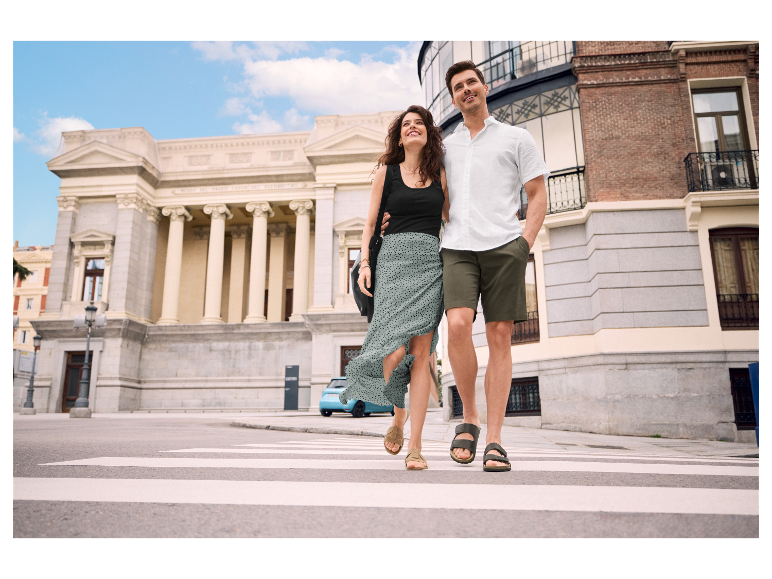 Ein Paar geht Hand in Hand über einen Zebrastreifen.