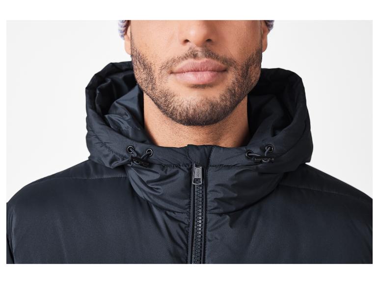 Bärtiger Mann trägt eine schwarze Kapuzenjacke und eine Strickmütze.