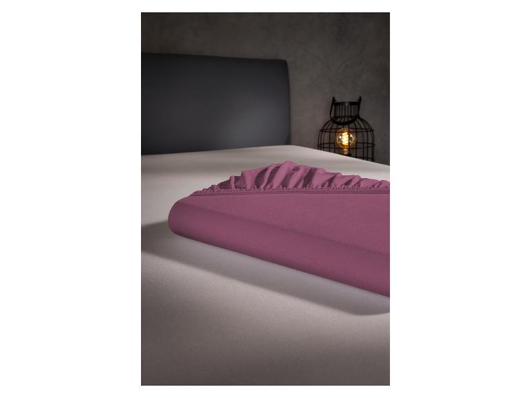 Lila Spannbettlaken auf einem Bett, im Hintergrund eine dekorative Laterne.