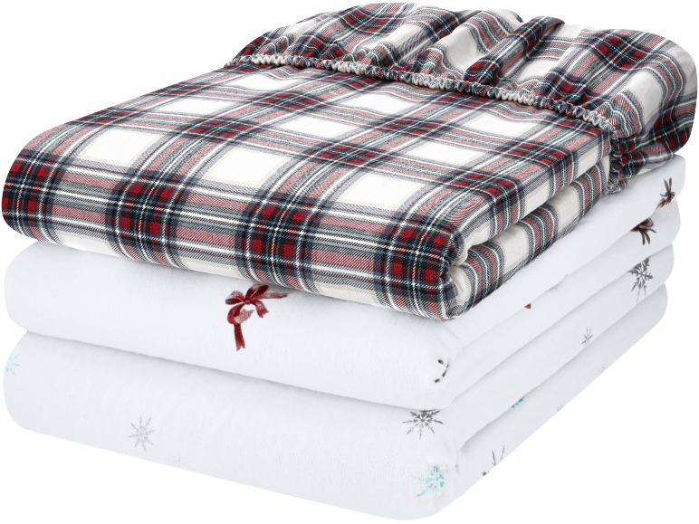 Gefaltete Bettwäsche mit rot-weißem Karomuster und weißen Laken mit Weihnachtsmotiven.