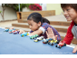 Zwei Kinder spielen mit bunten Spielzeugautos auf einem blauen Tisch.