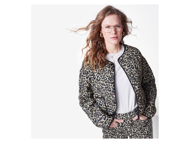 Frau trägt eine Leopardenmuster-Jacke und -Hose, ein weißes T-Shirt und eine Brille.