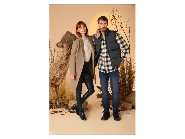 Ein Mann und eine Frau präsentieren Herbst-/Wintermode: Mantel, Daunenweste und Jeans.