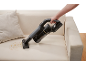 Kabelloser Handstaubsauger reinigt Krümel von einem beigen Sofa.