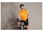 Ein Mann mit Fahrradhelm und einem orangenen Shirt mit dem Aufdruck 'Bike' sitzt auf einem schwarzen Fahrrad.