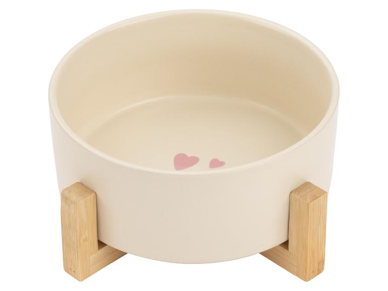 Cremefarbener Keramik-Futternapf für Haustiere auf Holzständer, verziert mit rosa Herzen.