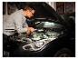 Mann mit Arbeitsleuchte »The Mechanic« inspiziert Automotor.