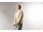 Eine Frau in einem beige Rollkragenpullover und einer grauen Hose.