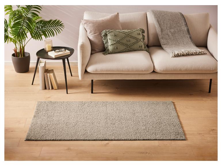 Ein grauer Teppich im Wohnzimmer mit einem weißen Sofa und einem grünen Kissen.