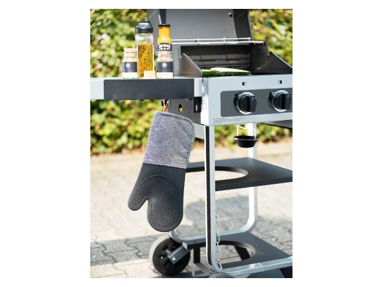 Topflappen hängt an einem Grill mit Gewürzen und Flaschen.