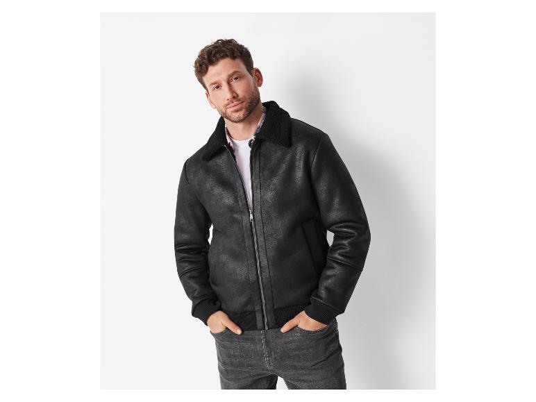 Mann in schwarzer Jacke mit Kunstfell und dunklen Jeans.