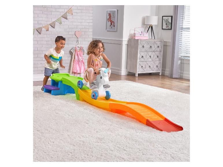 Kinder spielen mit einer Spielzeugrutsche mit Einhorn in einem Kinderzimmer.