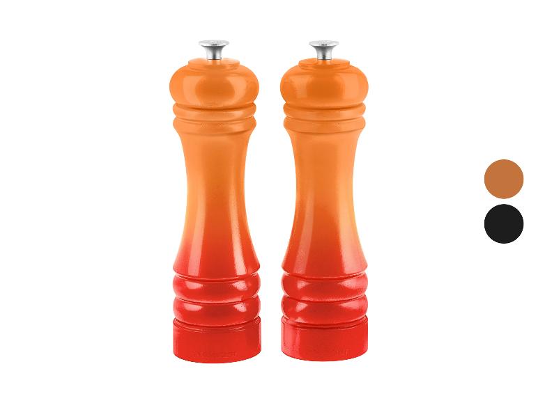 Zwei orange-rote Pfeffermühlen mit Farbverlauf, auf weißem Hintergrund stehend.