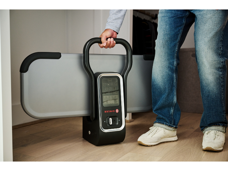 Ein Mann hält ein klappbares Fitnessgerät mit Digitalanzeige.