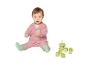 Baby in rosa Strickjacke und grünen Socken, spielt mit Bauklötzen und einem Stapelspielzeug.