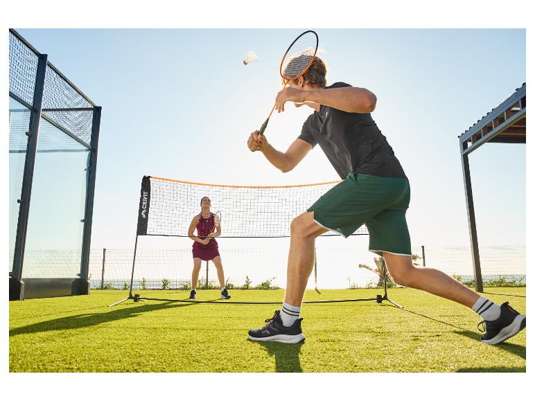 Zwei Personen spielen Badminton im Freien auf einem grünen Rasen mit Netz.