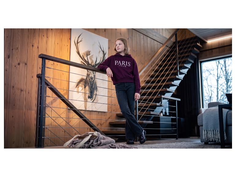 Mädchen in einem bordeauxroten Hoodie mit „PARIS AMOUR CLUB“-Aufschrift, schwarzen Jeans und glänzenden Schuhen.