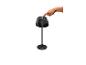 Eine Hand drückt den Einschaltknopf einer schwarzen Tischlampe mit plissiertem Schirm.