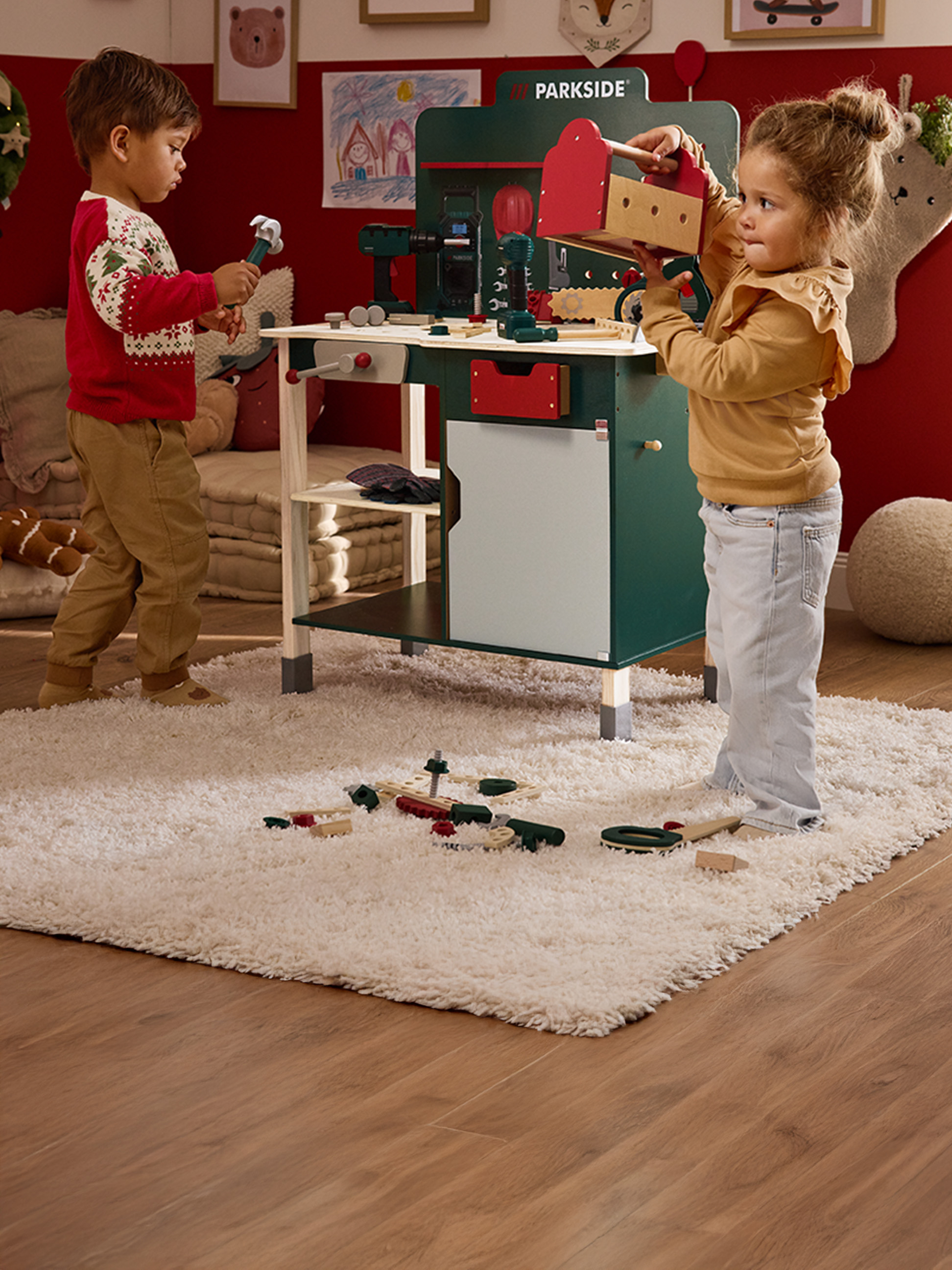 Zwei Kinder spielen mit einer Parkside Spielwerkbank und Holzwerkzeugen.