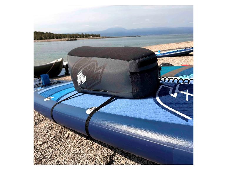 Blaues Paddleboard mit grauer Sitztasche an einem Kiesstrand.