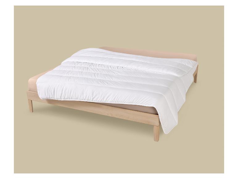 Weiße Bettdecke auf einem Holzbett mit beiger Bettwäsche