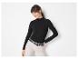 Frau in einem schwarzen gerippten Langarmshirt und heller Hose mit Gürtel.
