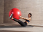 Eine Frau macht Bauchmuskelübungen mit einem Fitnessball auf einer Yogamatte.